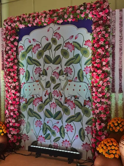 A beautiful backdrop featuring traditional 'Pichwai' art of cows, framed by a floral arch. This adds a unique and cultural touch to the ceremony.