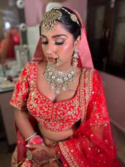 A classic bridal look with a neat bun that allows the heavy matha patti and nath to stand out. This hairstyle is perfect for a traditional Hindu wedding ceremony.