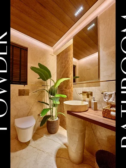 We designed this powder room to create a luxurious experience for guests. The space features a freestanding pedestal sink, warm marble walls, a wood-paneled ceiling, and a large plant to add a touch of nature.