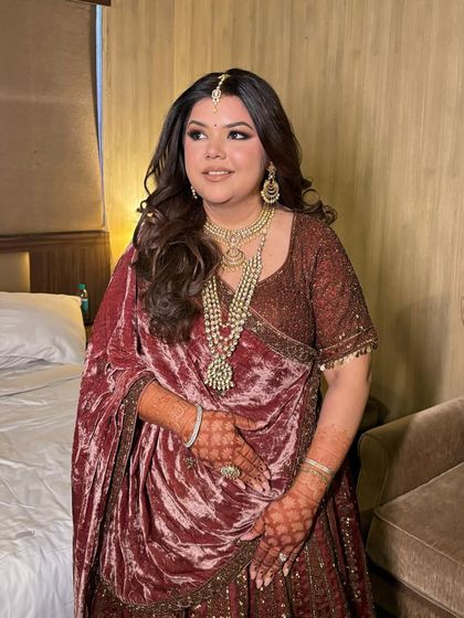 For Tisha's look, we went with a dramatic burgundy smokey eye and glossy lips, which perfectly complemented her deep-toned velvet lehenga.