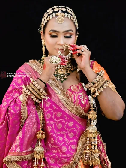 Adjusting the nath, a classic bridal moment. The makeup, with its warm tones and sharp contour, ensures the bride looks flawless from every angle.
