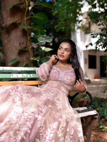 A model posing in a beautiful pink lehenga, showing off a subtle and elegant makeup look.