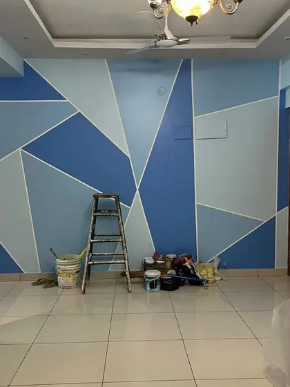 A living room accent wall featuring a geometric pattern in multiple shades of blue. This work-in-progress shot shows our process of building layers of color to create a dynamic and personalized space.