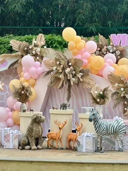 A wide shot of the pastel safari dessert table area, featuring a variety of animal figures and themed gift boxes.