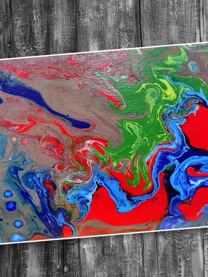 This fluid art piece uses a more controlled pour to create distinct rivers of red, blue, and green on a neutral background.