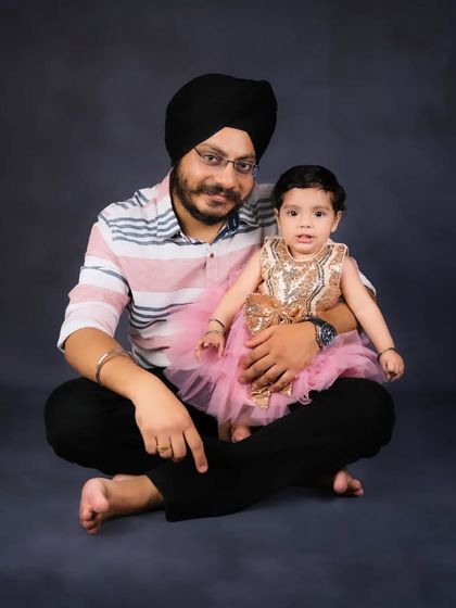 A sweet portrait of a father and his daughter. Her beautiful pink and gold dress shines against the dark background in this lovely photo.