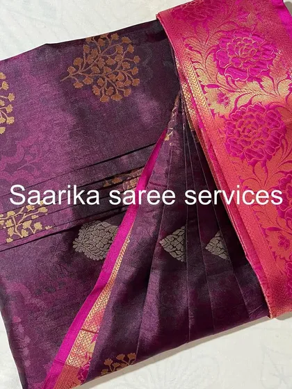 A purple saree with a bright pink and gold floral border.