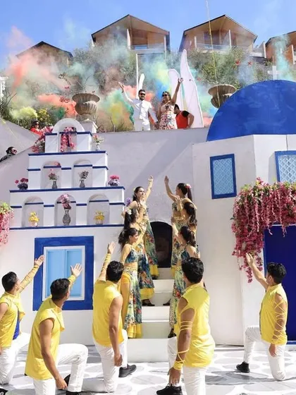 A wide shot of the Greece-themed carnival stage. Our dancers perform a lively routine as the couple makes their grand entrance, with the entire set designed to look like a Greek island.