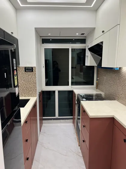 A full view of a compact U-shaped modular kitchen. We used a two-tone color scheme with terracotta and white to make the space feel larger, complemented by a patterned backsplash for a touch of character.