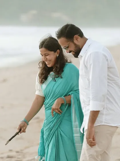 A playful moment captured as the couple examines something they've found on the beach, showcasing their shared curiosity and joy.