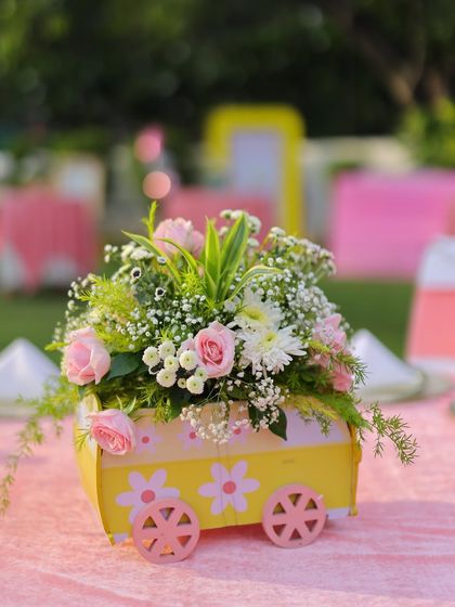 A close-up of the adorable wagon centerpiece, filled with fresh pink and white flowers. This small detail perfectly captures the sweet and sunny theme of the celebration.