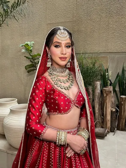 The complete traditional bridal look. With the dupatta gracefully draped, this styling highlights the rich red fabric and detailed gold work, creating a vision of timeless beauty.