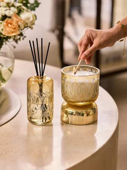 I believe in rituals, like the simple act of lighting a candle. Here, my Royal Haze candle and reed diffuser sit side by side, their hand-etched glass and golden hue bringing a touch of palatial elegance to a quiet moment. This set is perfect for creating a consistent layer of the rich Oud Bazaar fragrance in your living space.