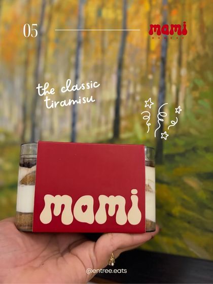 A handheld shot of a tiramisu jar from Mami Bombay. This gives a personal, relatable feel, as if a friend is recommending their favorite dessert. The branding is clear, and the dessert looks delicious.