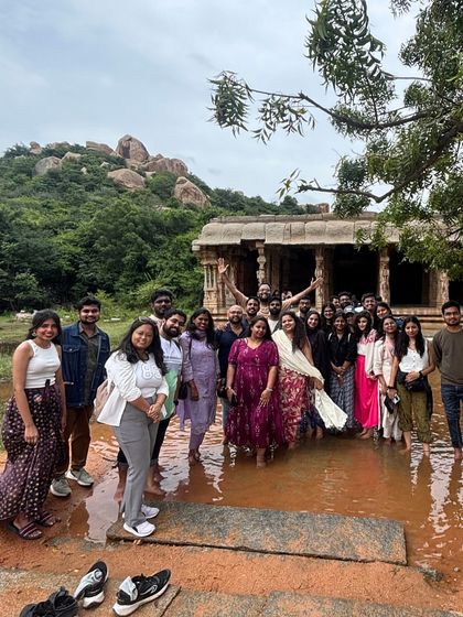 The group posing near a water-logged temple ruin in Hampi, a common sight during the post-monsoon season that adds to the site's beauty.