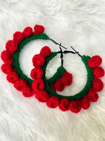 A close-up of the Christmas-themed crochet hoop earrings. The little red baubles are individually stitched onto the green hoop.