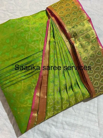 A parrot green saree with a pink and gold border.