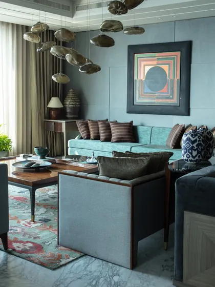Another angle of the art-centric living room, showing the interplay of the S.H. Raza painting with a custom Furgonomics armchair and a luxurious carpet from Jaipur Rugs.