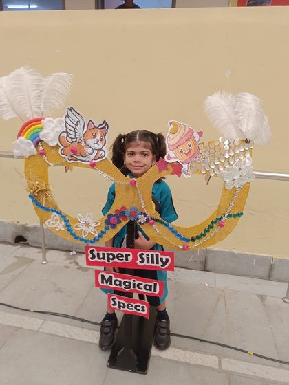 A young achiever poses with her creative prop after winning first position in the 'Talk-a-Tot' category at an inter-school competition.