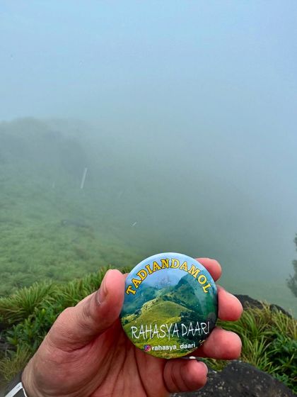 Our Tadiandamol trek badge, held against the misty hills of Coorg.