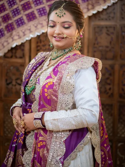 A serene and happy bride, her makeup perfectly complementing the rich purple and white outfit.