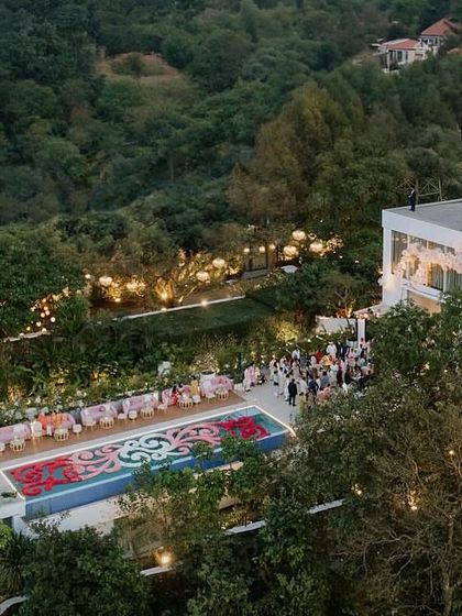 An aerial view of the picturesque 'Lagan Lakhwanu' ceremony we designed for Radhika Merchant and Anant Ambani. The event featured a stunning floral installation in the pool and a serene glasshouse, all nestled in lush greenery.