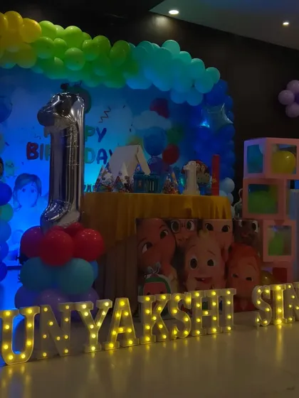 A full view of a Cocomelon-themed first birthday party, showing the extensive decorations and personalized marquee letters.