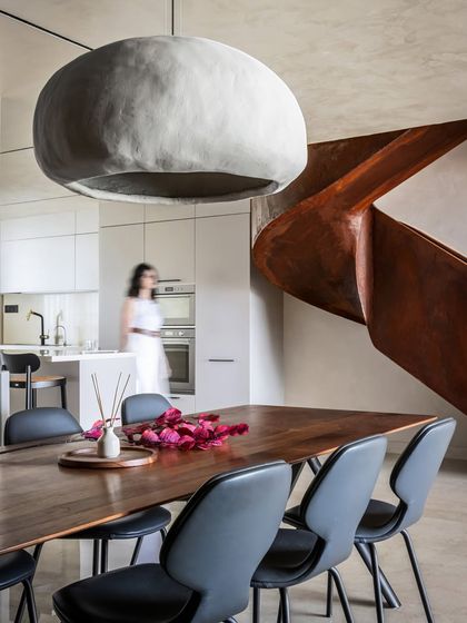 This shot captures the dynamic relationship between the dining area, kitchen, and the sweeping staircase. The open layout creates a sense of flow and unity, where luxury is not loud but quietly woven into every element.