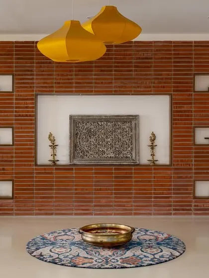 Another view of the 'Vasudhalayah' foyer, where the warm brick wall and illuminated niches create a dramatic and welcoming first impression.