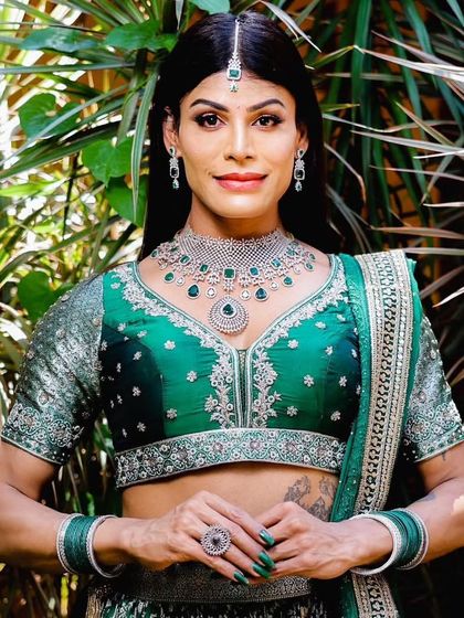 A close-up portrait of the model, highlighting the intricate details of the necklace and maang tikka.