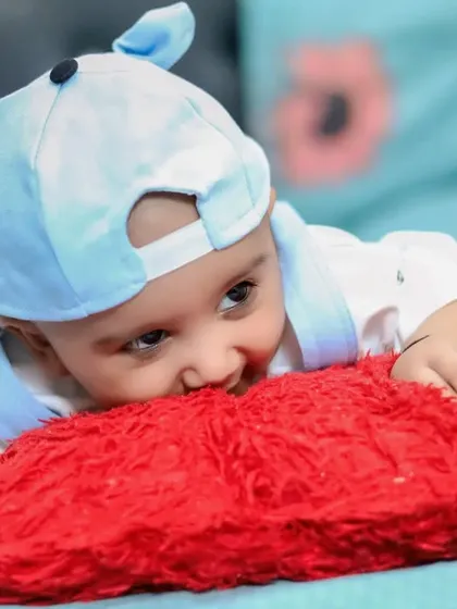 A playful moment as a baby chews on a soft red pillow. These candid shots show the curious and fun side of your baby's personality.