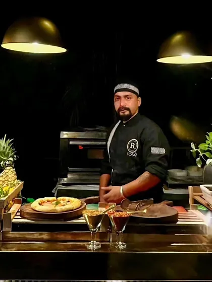 A portrait of our chef at the live pizza station, ready to craft wood-fired pizzas for your guests. We specialize in creating unforgettable experiences for opulent weddings and grand corporate events.