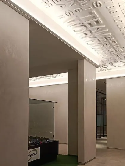 In this office space, cove lighting is used in a creative way to highlight the three-dimensional motivational text on the ceiling. This detail turns a simple transitional area into an inspiring brand statement, showcasing how light can interact with architectural features.
