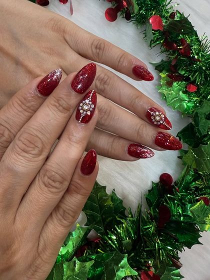 The full two-hand view of the red Christmas nails, beautifully framed by festive holly.