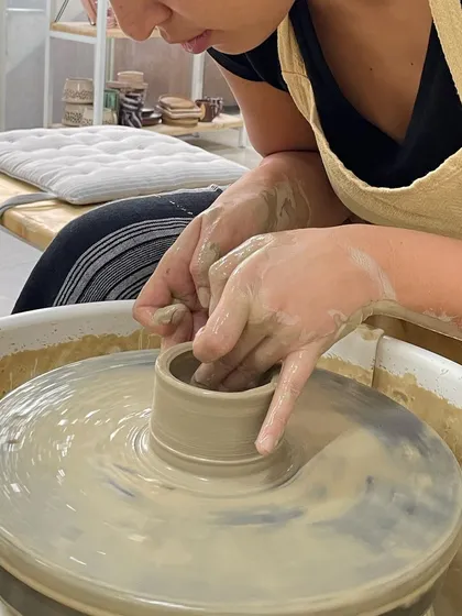 A close-up of a student learning to pull the clay upwards. This technique requires a delicate touch to create even walls for a cup or small vase.