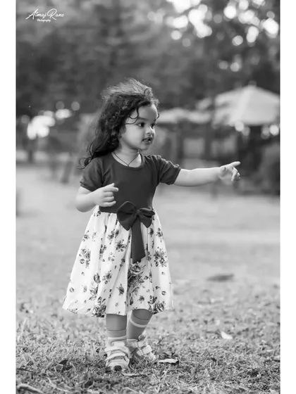 A candid black and white photo of Riona pointing at something off-camera. This captures a moment of discovery and curiosity during her outdoor playtime.