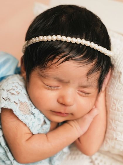 A close-up portrait of a sleeping newborn in delicate blue lace. This shot focuses on the serene face, tiny hands, and the peacefulness of the first few weeks.