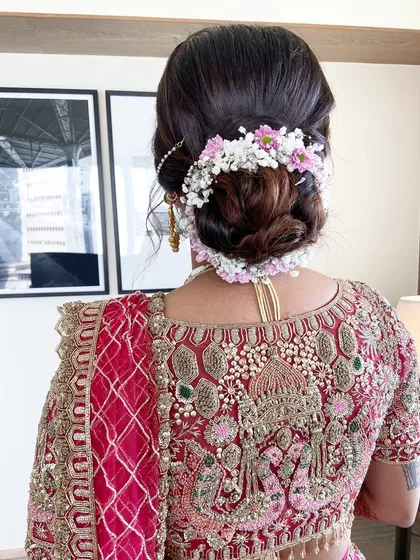 A detailed shot of a floral bridal bun. I used a mix of baby's breath and other small pink flowers to create this rich, textured look that complements the bride's embroidered blouse.