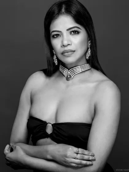 A classic black and white portrait showcasing a diamond and emerald choker. The focus is entirely on the model's expression and the intricate jewellery.