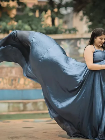 The deep, satin-finish blue of this gown creates a sense of elegance and royalty. The tossing train effect adds a dynamic and artistic element to your maternity portraits.