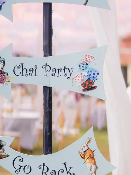 A quirky directional sign from the 'Alice in Wonderland' Mehendi, pointing guests to the "Chai Party."