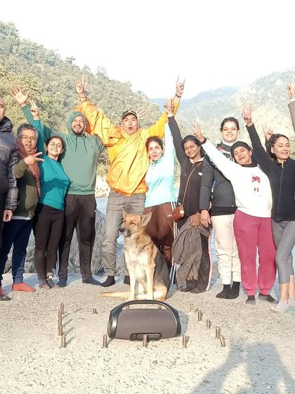 A cheerful group photo by the river, with our four-legged friend joining in. Everyone is part of the tribe.