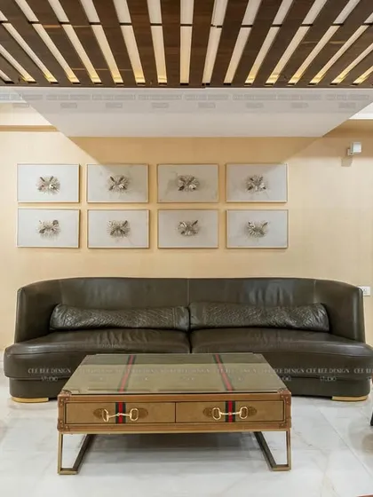 A full view of the living area from image 112, with a dark leather sofa and orange-tufted accent chairs.