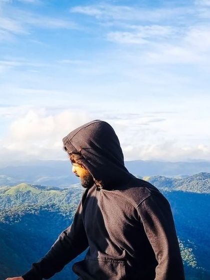 A close up of a traveler looking out over the blue tinged mountains of Coorg. The views from these heights are truly unforgettable.