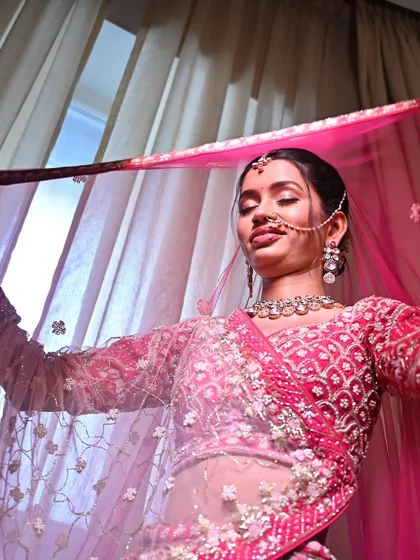A playful and happy moment. Her radiant makeup and bright pink lehenga come together to create a look of pure bridal joy.