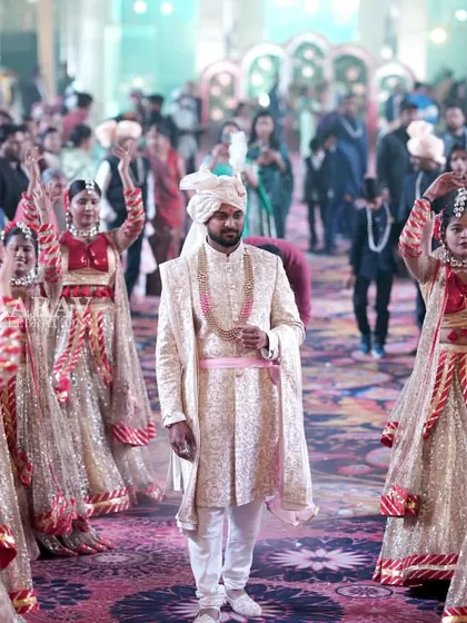 A wide-angle view of a groom's grand entry, showing him surrounded by guests and a large troupe of dancers. The energy of the crowd combined with the choreography makes for a spectacular welcome.