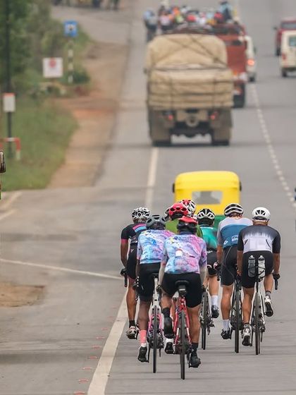 The peloton shares the road with everyday traffic, a common challenge in Indian road racing that our riders handle with skill.