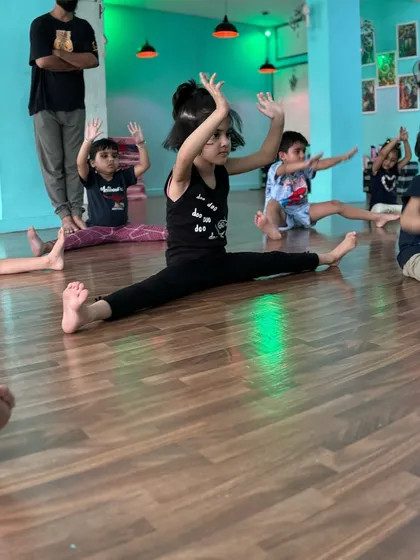 This student shows off her impressive center split, holding her arms up to demonstrate balance and core control. She is a great example for our beginners.