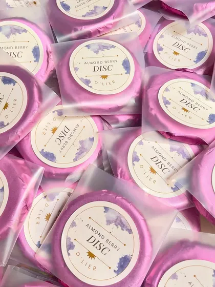 Our Almond Berry Discs, individually wrapped in vibrant pink foil with custom labels. They make for beautiful and delicious additions to any gift hamper or party favor bag.