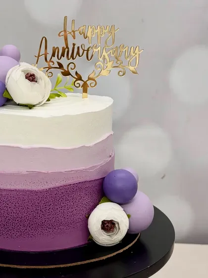 A different angle of the purple anniversary cake, showing off the 'Happy Anniversary' topper and the balance of colors.